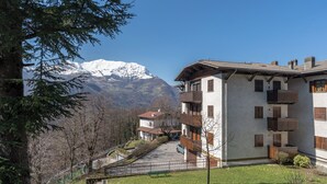 Un edificio con balcón y vistas a montañas nevadas.