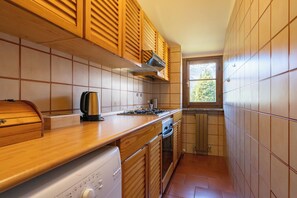 Een koelkast, een oven, een kookplaat, kookgerei, borden en bestek