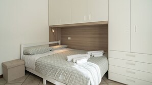 Een slaapkamer met een bed, nachtkastje, kledingkast en een bijzettafeltje.