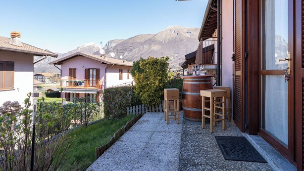 Een woongebouw met balkon, een houten vat en een bergzicht op de achtergrond.