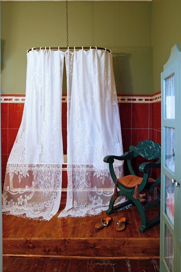 A room with a wooden floor, a green chair, and a white lace curtain. - Seaside Neoclassical Property in Vaporia Ermoupoli (Syros)
