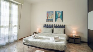 A bedroom with a bed, two pillows, a nightstand, a lamp, and two wall art pieces. - Piani di Bobbio Adventure Base (Cremeno)