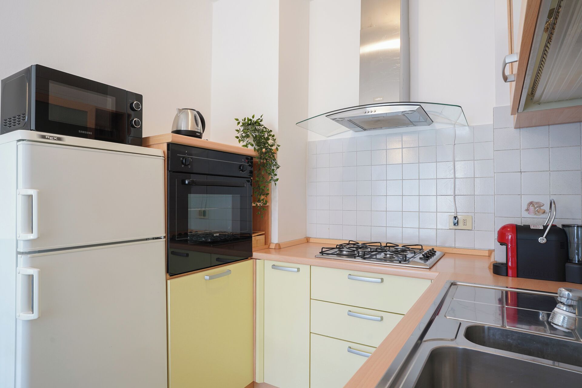 A compact kitchen with a microwave, oven, gas stove, and a sink.