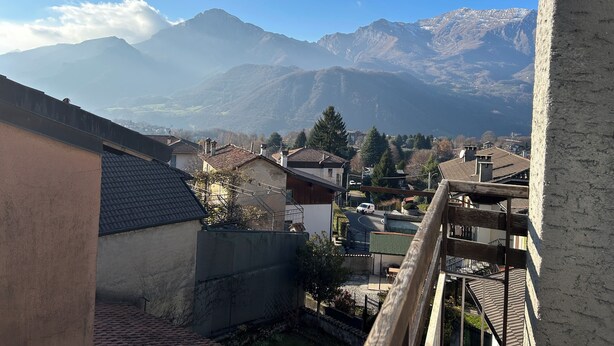 A residential area with houses, a wooden fence, and a mountain range in the background. - Piani di Bobbio Adventure Base (Cremeno)