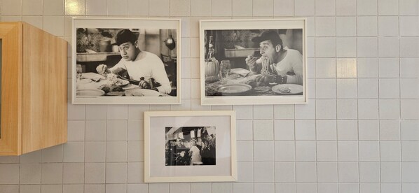 Tres fotografías blanco y negro de escenas de comedor en una pared de azulejos.