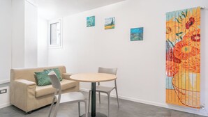 Ett modernt rum med en beige soffa, ett runt bord och tre tavlor på väggen.
