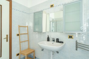 Een badkamer met een witte wastafel, een spiegel en een houten ladder.