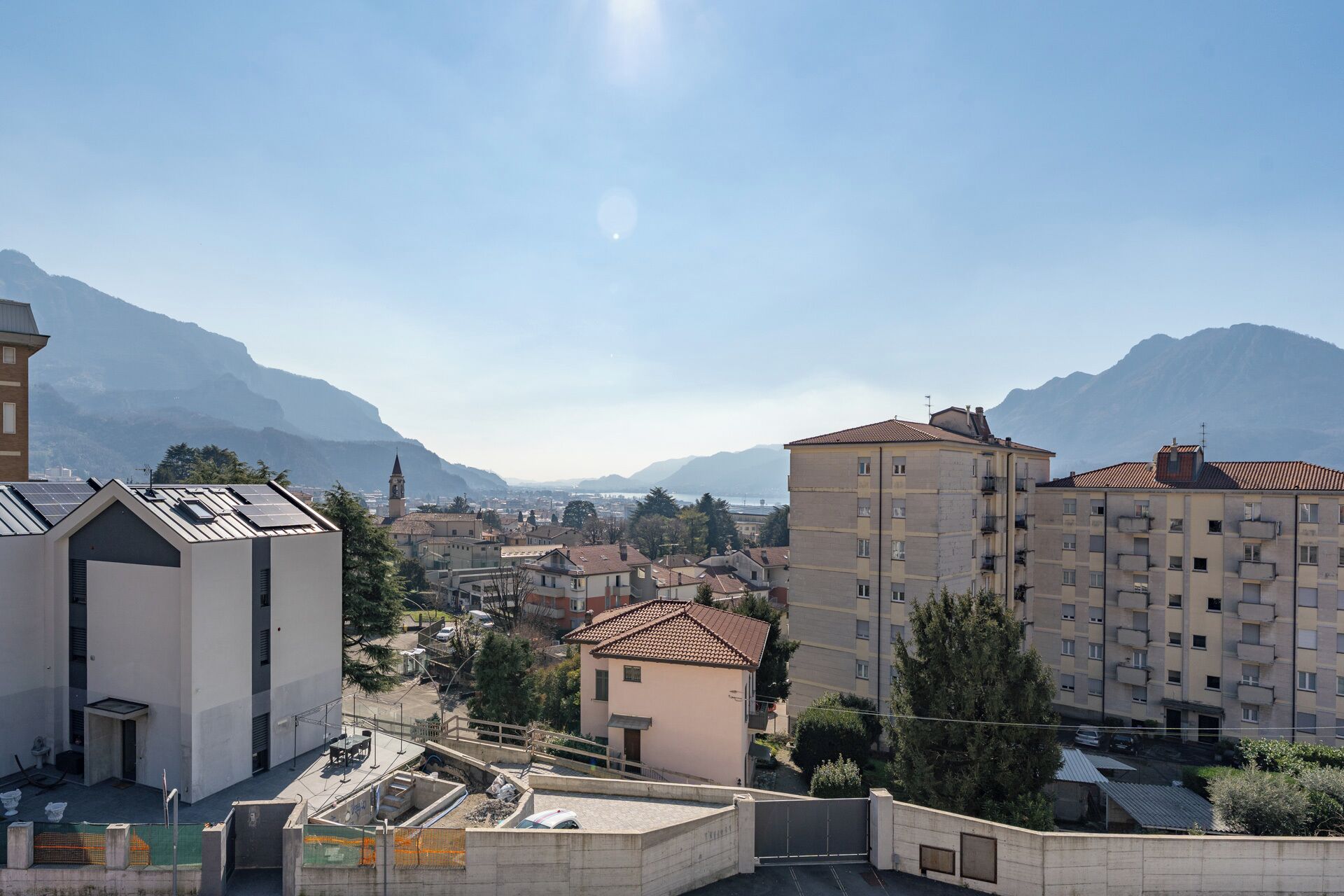 A residential area with apartment buildings, a church tower, and mountains in the background.