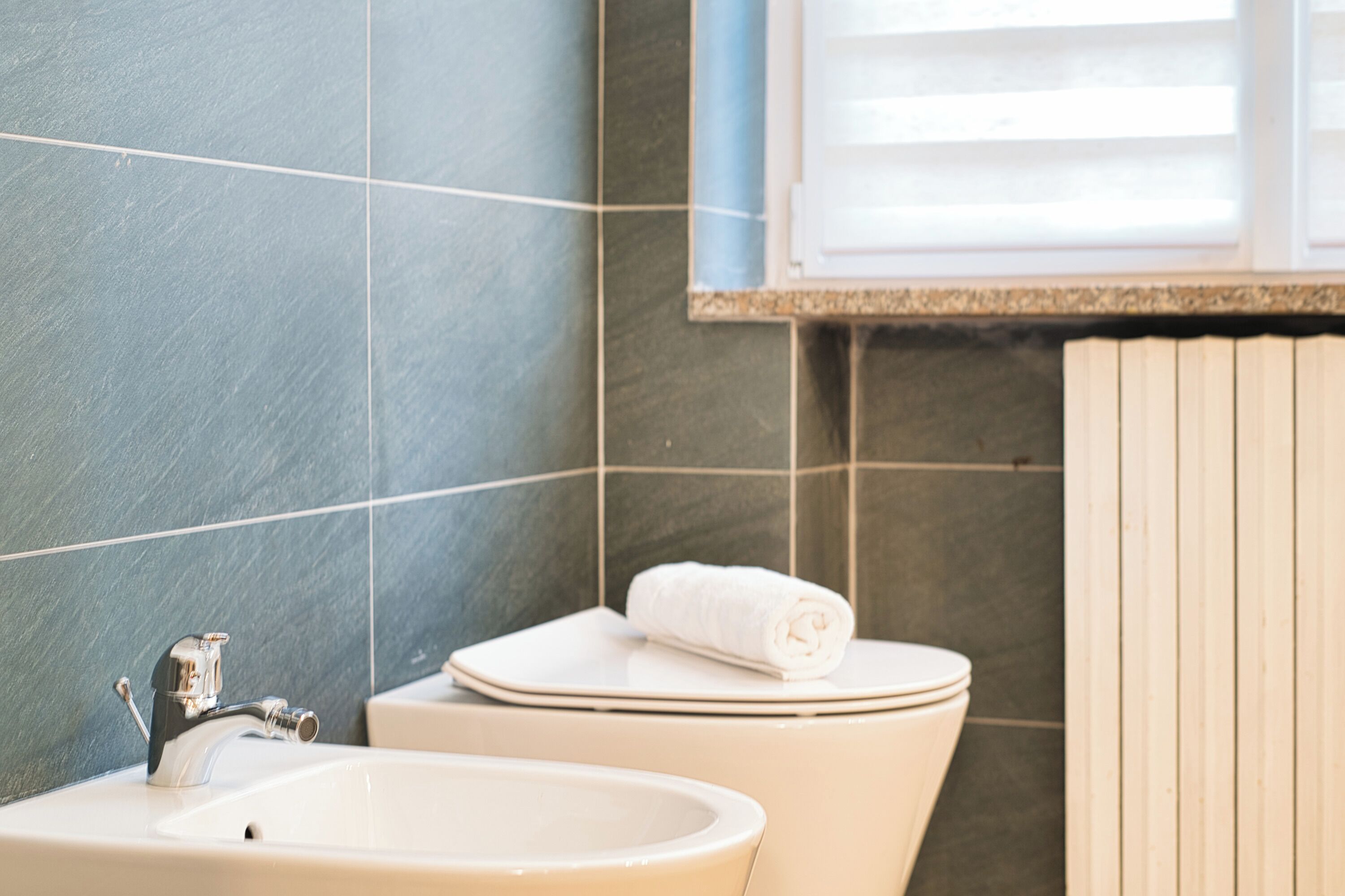 A bathroom with a sink, toilet, and window.