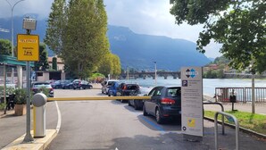 Ein Parkplatz mit einer gelben Barriere, einem Telepass-Schild und einem Schild für 'Parchessco Via Adda' mit einer 24-Stunden-Parkhinweis.