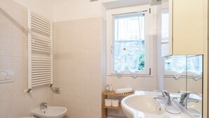 Baño con bidé, inodoro, lavamanos y ventana con vista a zonas verdes.