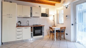 Una cocina compacta con armarios blancos, horno integrado y un comedor con mesa y sillas.