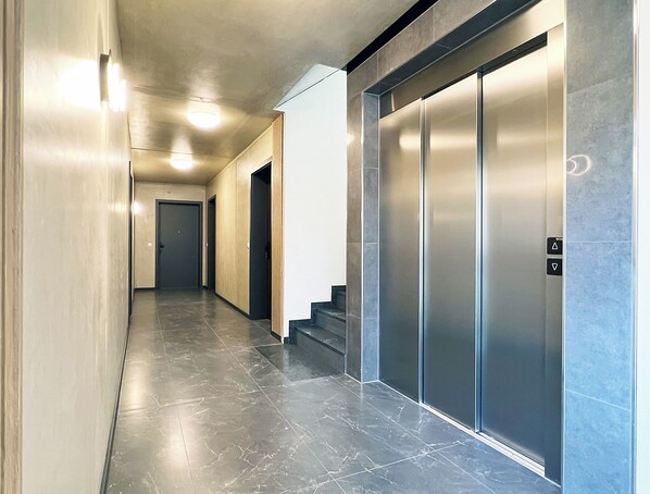 Ein moderner Flur mit Marmorboden, einer Treppe und einem wandmontierten Aufzug.