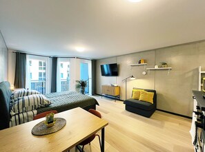 Eine moderne Wohnung mit Bett, Sofa, Esstisch und einem an der Wand befestigten Fernseher.