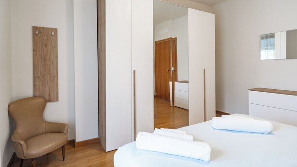 A modern bedroom with a bed, a chair, a wardrobe, and a mirror. - Lecco Isola - Top Apartment near Viscontea Island (Lecco)