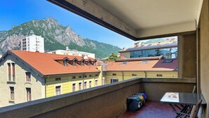 A balcony with a view of mountains, a table, and a chair. - Lecco Isola - Top Apartment near Viscontea Island (Lecco)