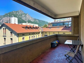 Un balcon avec vue sur les montagnes, une table et une chaise.
