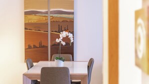 A dining area with a table, chairs, and a painting of a landscape. - Lecco Isola - Top Apartment near Viscontea Island (Lecco)