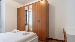 Ein Schlafzimmer mit einem Bett, einem Holzschrank und einem Spiegel.
