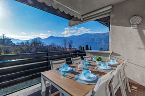 A dining area with a table set for two, overlooking a mountainous landscape. - Blu Al Lago - Lago di Como (Lierna)