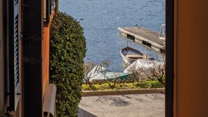 A view from a window overlooking a lake with boats docked at a pier, surrounded by hills. - Riva Granda - Falcone (Mandello del Lario)