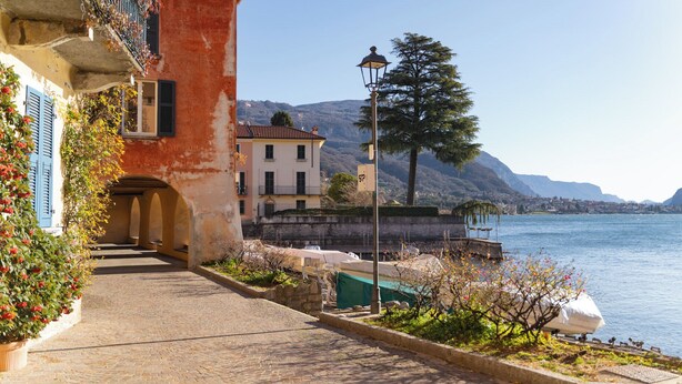 A cobblestone pathway leading to a building with a red facade and blue shutters. - Riva Granda - Falcone (Mandello del Lario)
