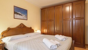 Habitación de hotel con una cama grande, un armario de madera y un cuadro enmarcado en la pared.