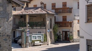 Una plaza tradicional de pueblo europeo con adoquines, una torre del reloj y edificios con balcones y contraventanas de madera.