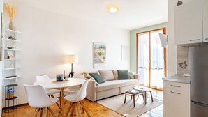 A modern kitchen with white cabinets, a stainless steel refrigerator, and a dining area with a white table and chairs. - Relaxing Lake Gem - One Bedroom Apartment, Sleeps 4 (Perledo)