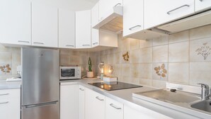 A modern kitchen with white cabinets, a stainless steel refrigerator, a microwave, and a built-in oven. - Relaxing Lake Gem - One Bedroom Apartment, Sleeps 4 (Perledo)