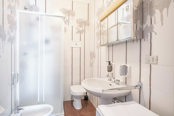 Un baño con ducha, inodoro, lavabo y espejo.