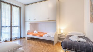 A bedroom with a bunk bed, a single bed, a bedside table with a lamp, and a window with sheer curtains. - ValleyHideaway with private garden near Como lake (Taceno)