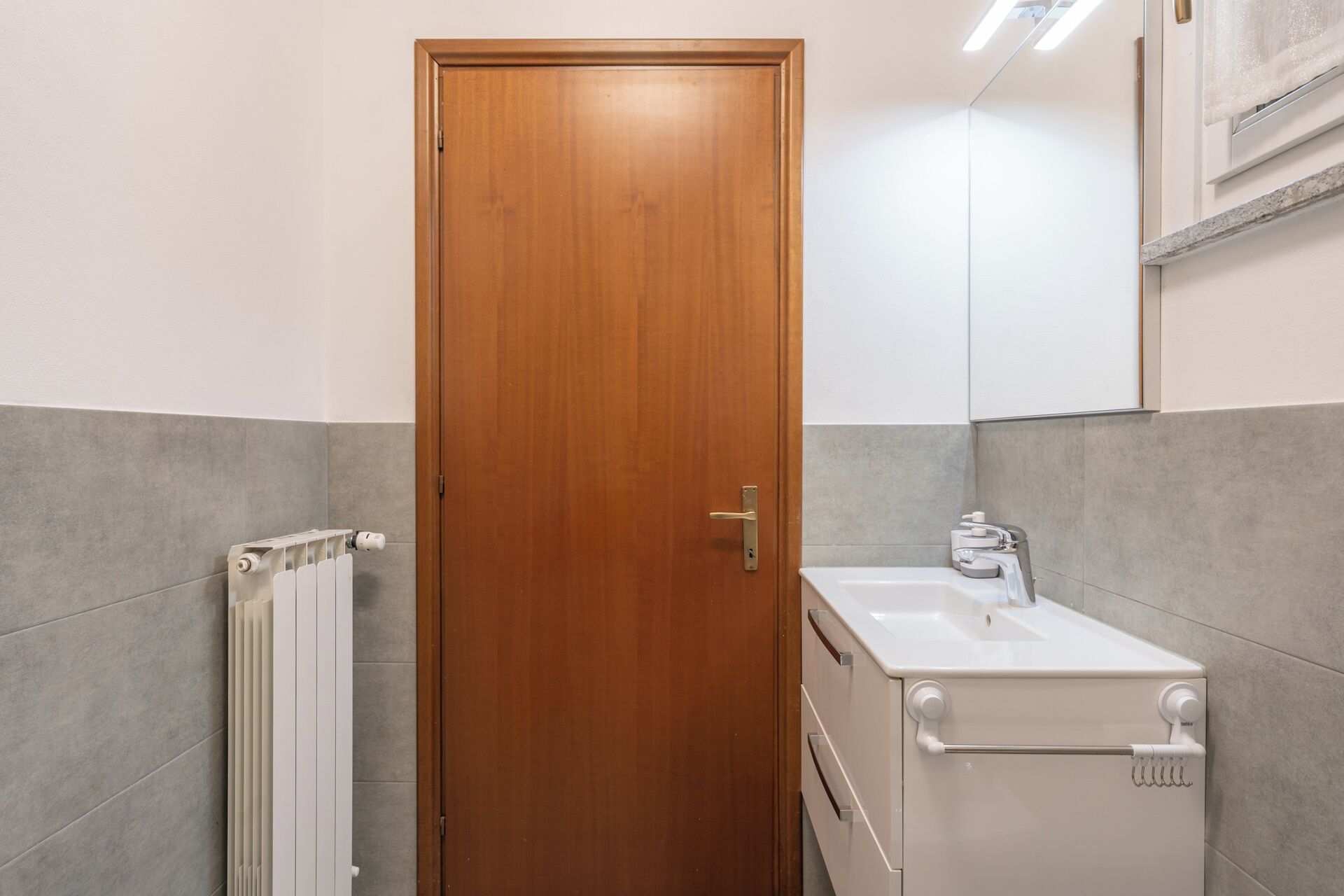 Une salle de bain avec une porte en bois, un lavabo blanc et un porte-serviettes.