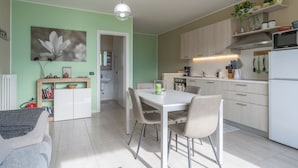 Una cocina moderna con armarios blancos, una mesa de comedor con sillas y un refrigerador.