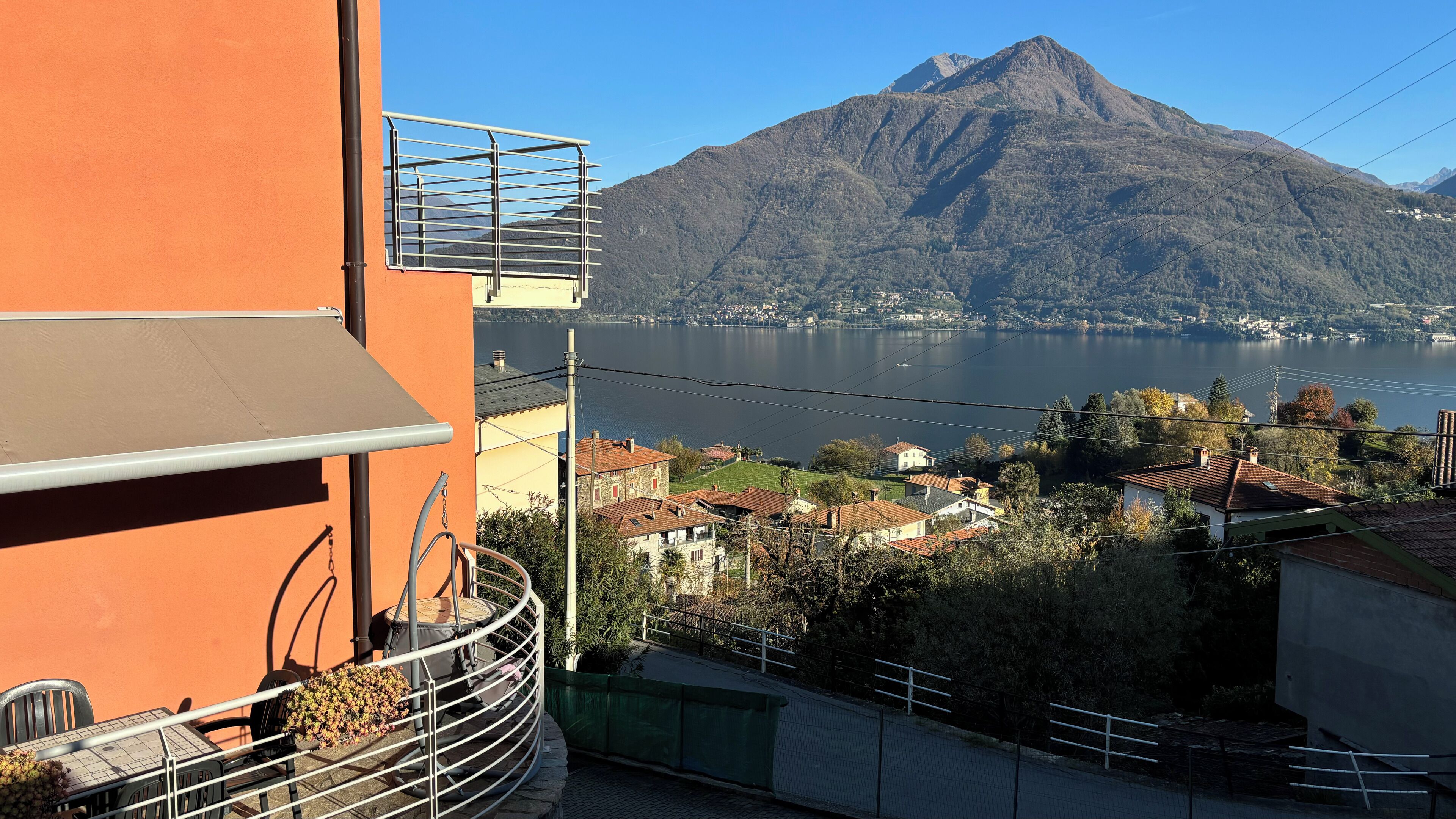 Un balcon doté d’une balustrade en métal, donnant sur un lac et une montagne.