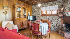 Un salon chaleureux avec un meuble en bois, un téléviseur, une cheminée et un coin repas comprenant des chaises et une table.