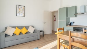 Una sala de estar con un sofá gris, cojines amarillos y una obra de arte floral enmarcada en la pared.