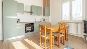 Una cocina compacta con comedor, que incluye un horno empotrado, microondas y un ventanal con cortinas.