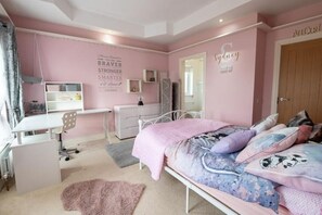 Ett sovrum med rosa tema, inrett med en säng, ett skrivbord och en garderob.