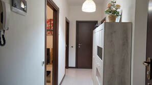 Un pasillo con puerta de madera, un teléfono en la pared y una lámpara colgante.