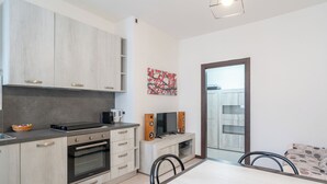 Una cocina moderna con horno integrado, cafetera y comedor con mesa y sillas.