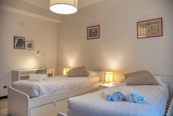 Una habitación de hotel con dos camas, un escritorio y una lámpara.