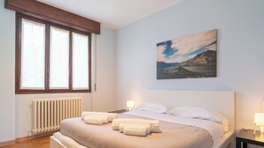 Une chambre à coucher avec un lit, une fenêtre, un radiateur et un tableau au mur.