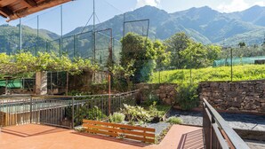 Un jardin en terrasses avec des murets en pierre, un banc en bois et une clôture en métal.
