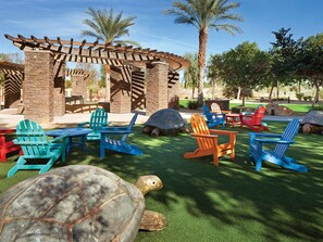 A patio area with Adirondack chairs, a wooden pergola, and a turtle sculpture. - Marriott's Shadow Ridge  Studio Suite (Palm Desert)