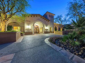 A hotel entrance with a stone facade, arched doorways, and a landscaped driveway.