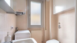 Une petite salle de bain bien éclairée, équipée d'une baignoire, de toilettes et d'un bidet.