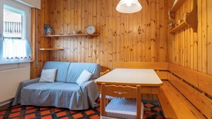 Une pièce chaleureuse avec un mur en bois, un canapé bleu agrémenté de coussins blancs, une table en bois et une horloge au mur.