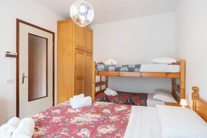 A room with a bunk bed, a wooden wardrobe, and a door with a textured panel.