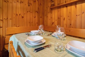 A dining table set with white plates, bowls, and wine glasses, with a wooden bench and a green tablecloth. - Oasi Valleverde - One Bedroom Apartment, Sleeps 4 (Pasturo)